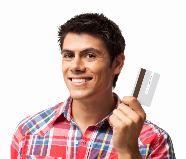 Portrait of young man smiling while holding credit card. Horizontal shot. Isolated on white.